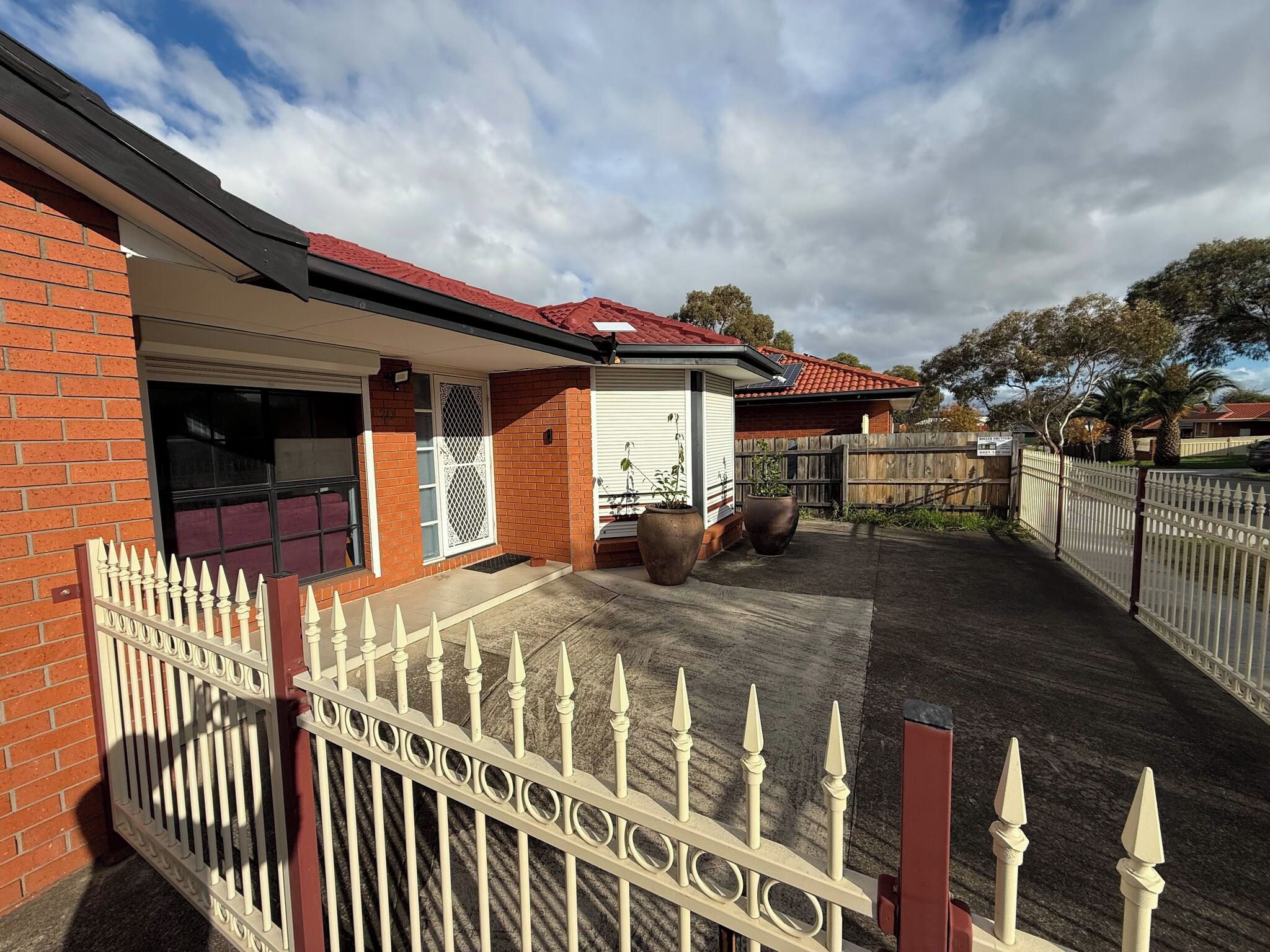 A residential property with a brick exterior, a covered patio area, and a fenced backyard.