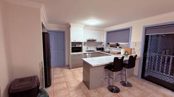 Cozinha compacta com ilha central, banquetas e área de refeições.