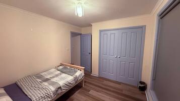 A bedroom with a single bed, a wardrobe, and a door.