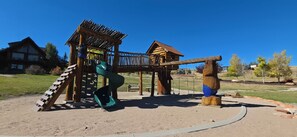 A playground with a slide, climbing structure, and swings. - Two Bear Lodge | Sleeps 35 | Beach, Pools & Views (Fish Haven)