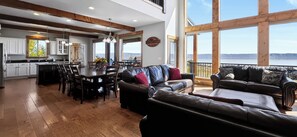 A spacious living area with a dining table, leather sofas, and a view of the outdoors. - Two Bear Lodge | Sleeps 35 | Beach, Pools & Views (Fish Haven)