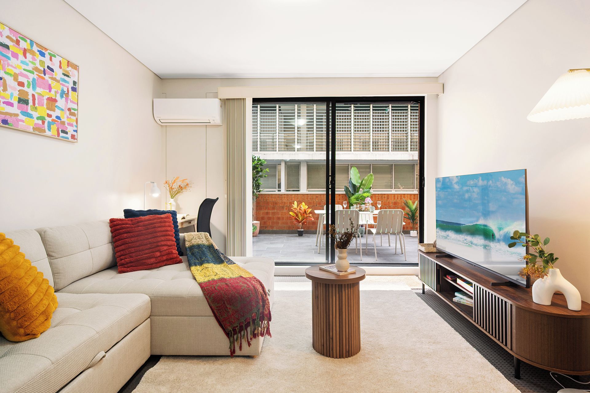 A modern living room with a sofa, a coffee table, and a flat-screen TV.