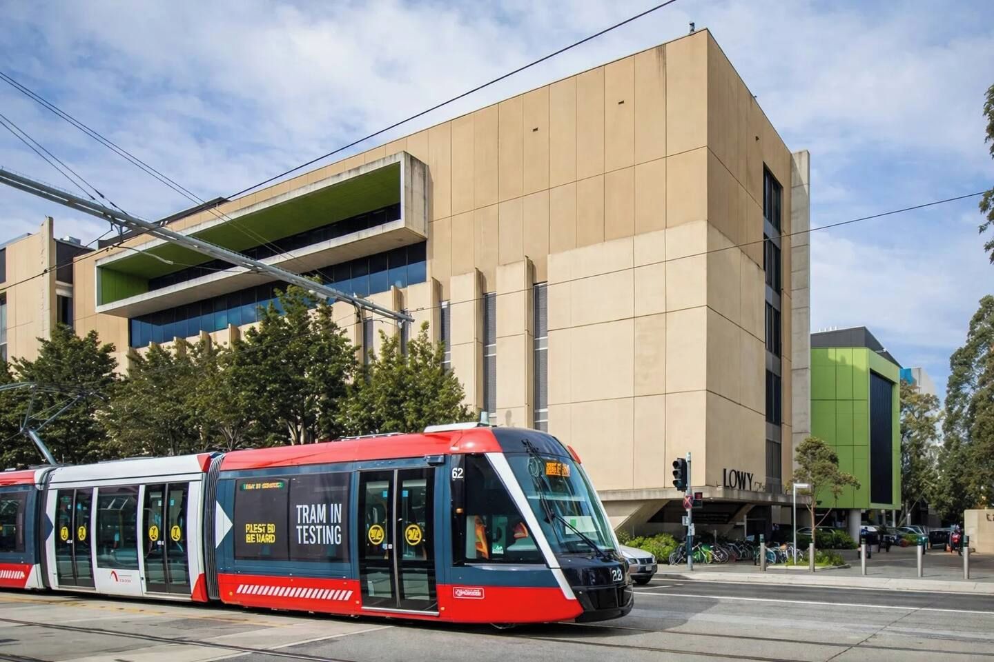 A tram in motion with a modern building in the background.