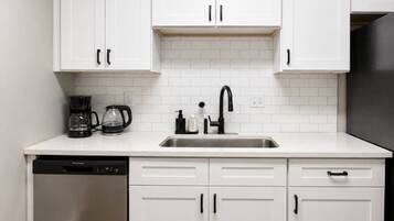 A kitchen with white cabinets, a stainless steel sink, and a dishwasher.