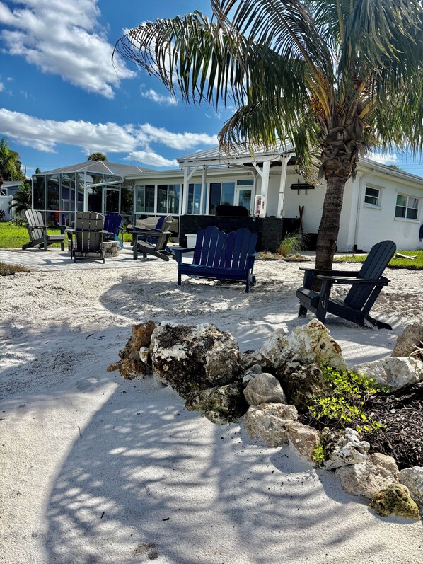 Une propriété située en bord de mer, dotée d’un espace salon couvert, de chaises longues et d’un palmier.