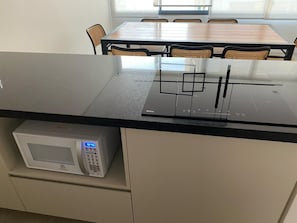 A kitchen with a microwave, a stove, and a dining table with chairs. - Brand-New Studio 150m from Vila Madalena Metro WSS144 (São Paulo)