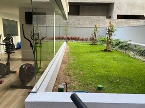 Ein moderner Außenbereich mit gepflegtem Rasen, Trainingsgeräten und einer Glasabtrennung.