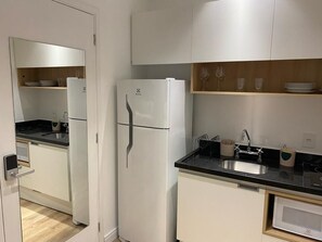 Ett modernt kök med vita skåp, en svart bänkskiva och en inbyggd diskmaskin.