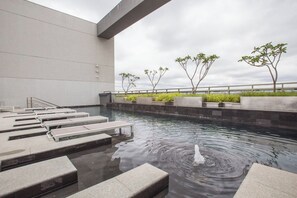 Ein moderner, überdachter Pool mit abgestuften Sitzplätzen und einem Wasserspiel.