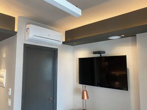 Ein Zimmer mit geschlossener Tür, einem wandmontierten Flachbildfernseher und einer Wandklimaanlage.