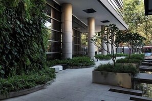 Un camino que lleva a un edificio de diseño moderno, con una serie de columnas y un paseo techado.