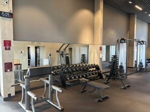 A gym with weightlifting equipment, benches, and a mirrored wall. - Studio w/ Pool & Parking – Near Oscar Freire Metro VNCV306 (São Paulo)
