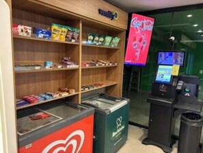 Ein Automatenbereich mit Snacks und Getränken, ein Coca-Cola-Kühlschrank und ein digitaler Bildschirm.