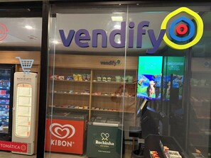 A storefront with a vending machine, shelves stocked with products, and a digital display. - Studio w/ Pool & Parking – Near Oscar Freire Metro VNCV306 (São Paulo)