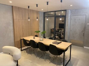A modern dining area with a wooden table, black chairs, and pendant lighting. - Brand-New Studio near Brooklin Metro HMB616 (São Paulo)