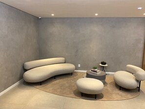 A modern living room with a curved sofa set, a round coffee table, and a small side table with a plant. - Brand-New Studio near Brooklin Metro HMB616 (São Paulo)