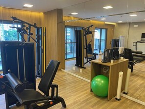 A gym with exercise equipment, a green exercise ball, and a coffee station. - Brand-New Studio near Brooklin Metro HMB616 (São Paulo)