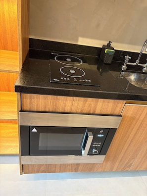 Ett kök med en svart bänkskiva, en inbyggd ugn och en diskho i rostfritt stål.