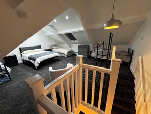 A bedroom with a sloped ceiling, a bed, a dresser, a chair, and a staircase. - Lovely 3-bedroom apartment in South Shields near the coast (South Shields)