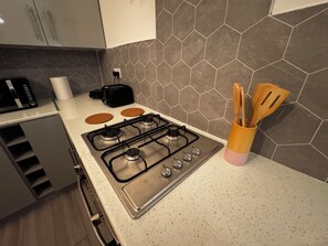 A kitchen with a gas stove, a toaster, and a utensil holder. - Lovely 3-bedroom apartment in South Shields near the coast (South Shields)