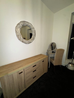 A room with a wooden cabinet, a desk, a chair, and a wall-mounted mirror. - Lovely 3-bedroom apartment in South Shields near the coast (South Shields)