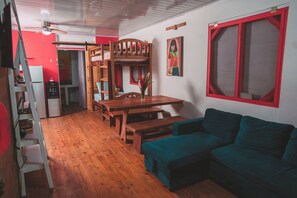 A compact living space with a bunk bed, a dining table, and a sofa.