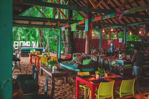An outdoor seating area with colorful furniture, a bar, and a view of the beach.