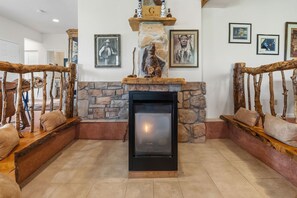 A stone fireplace with a black glass door, flanked by wooden benches with cushions, and framed pictures on the walls. - Sweet Home Colorado!!!! Where the skies are Crystal Blue!!!! (Kremmling)