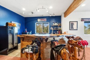 A bar area with a wooden counter, a refrigerator, and shelves with bottles. - Sweet Home Colorado!!!! Where the skies are Crystal Blue!!!! (Kremmling)