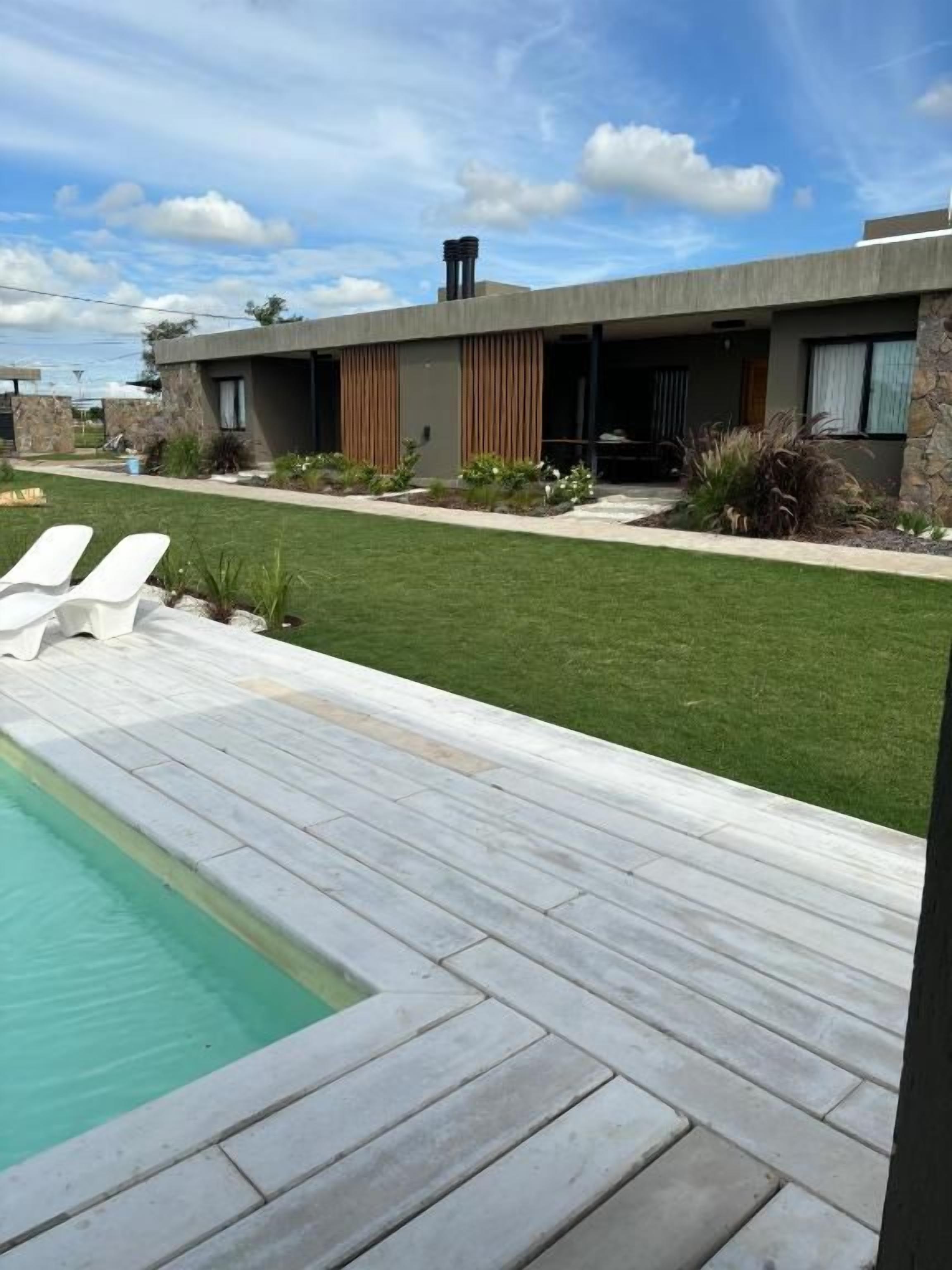 A modern house with a swimming pool, a well-maintained lawn, and a patio area.