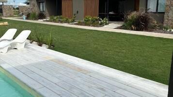 A modern house with a swimming pool, a well-maintained lawn, and a patio area.