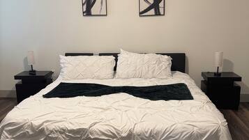 A bedroom with a bed, two nightstands, a ceiling fan, and abstract wall art.