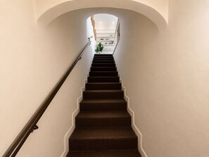 A staircase with a handrail leading to a landing with a plant and a shelf. - New! Marvellous Penthouse on Piazza Rondanini (Roma)