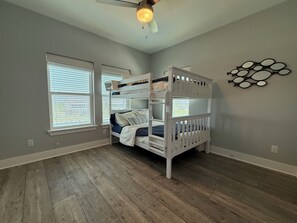 Ein Zimmer mit einem Etagenbett, einem Deckenventilator und einem Fenster mit Jalousien.
