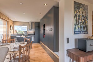 Eine moderne Küche mit dunklen Schränken, einem Essbereich mit Holzstühlen und einem Bild an der Wand.