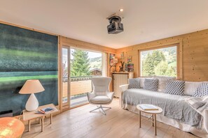 Ein modernes Wohnzimmer mit großem Fenster, einem weißen Sofa, einer Lampe und einem kleinen Tisch.