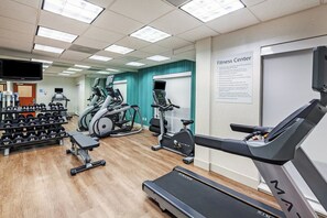 Centre de fitness amb cintes de córrer, el·líptiques i diferents tipus de pèses.