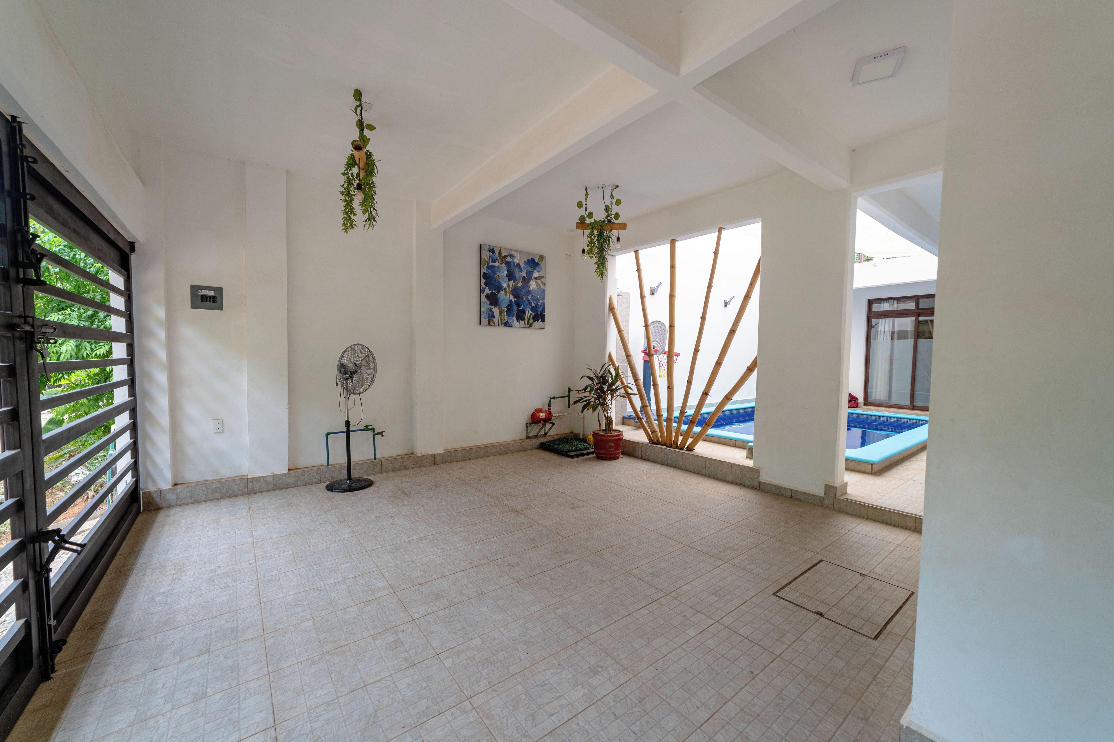Une pièce spacieuse avec un sol carrelé, un ventilateur, un tableau et une vue sur une piscine.