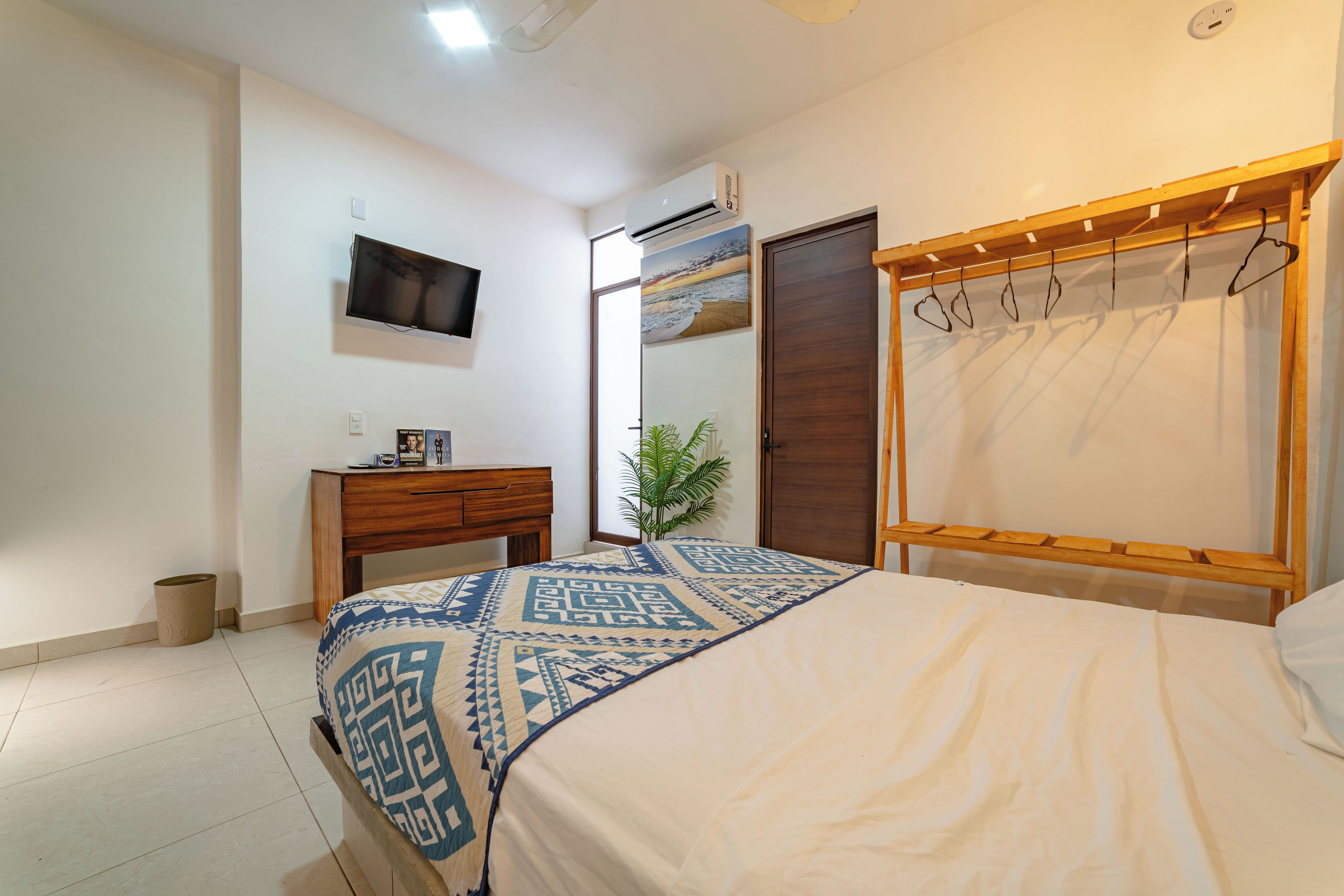 Une chambre à coucher comprenant un lit, un bureau, une télévision, une armoire et un miroir.