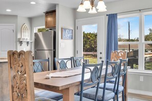 A dining area with a wooden table and chairs, a refrigerator, and a window with a view of the outdoors. - Pet-Friendly 3-bedroom house walking distance to Canyon Lake and Comal Park (Canyon Lake)