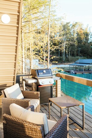 Una terrazza esterna con mobili in vimini, un barbecue e vista su una piscina.