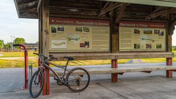 A wooden information board with maps and text, a bicycle, and a bench.