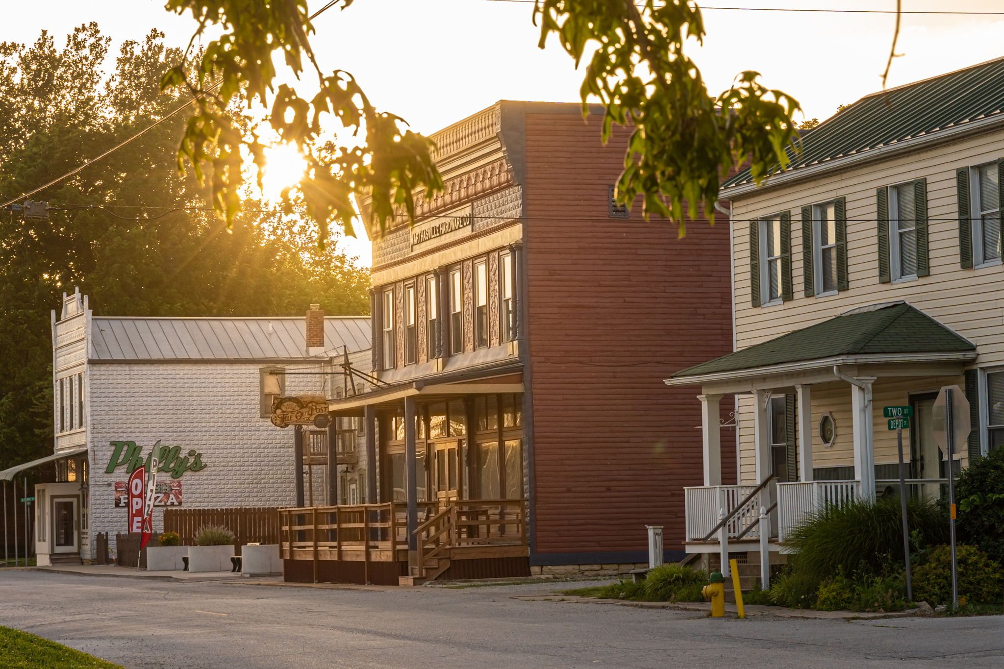 A building with a 'Pizza' sign, a porch, and a staircase leading to a second floor.