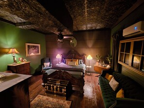 A room with a bed, a green sofa, a wooden dresser, a desk, and a ceiling with intricate designs. - NEW! The Gatsby Speakeasy - Marthasville,MO (Marthasville)