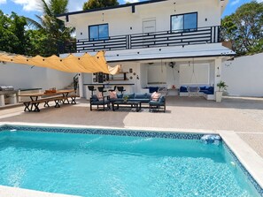 A two-story building with a swimming pool, outdoor seating area, and a covered patio. - BellaHills by Ambar (San Juan)