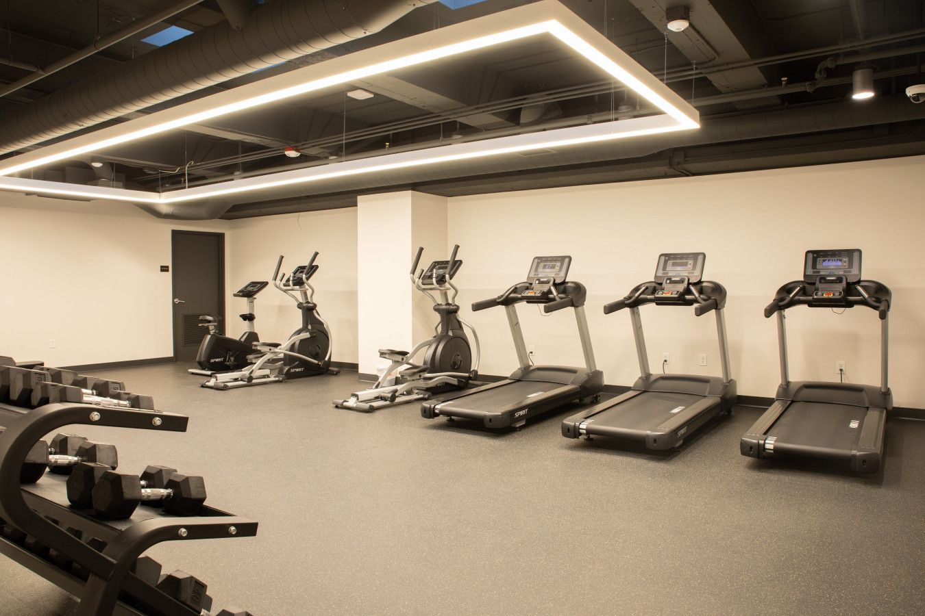 A gym with treadmills, elliptical machines, and weight benches.