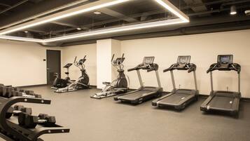 A gym with treadmills, elliptical machines, and weight benches.