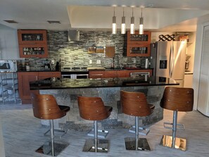 A modern kitchen with a central island, bar stools, and stainless steel appliances. - Private pool screened in—minutes from Bonita Beach. 2 Master Beds / 2.5 Baths. (Bonita Springs)