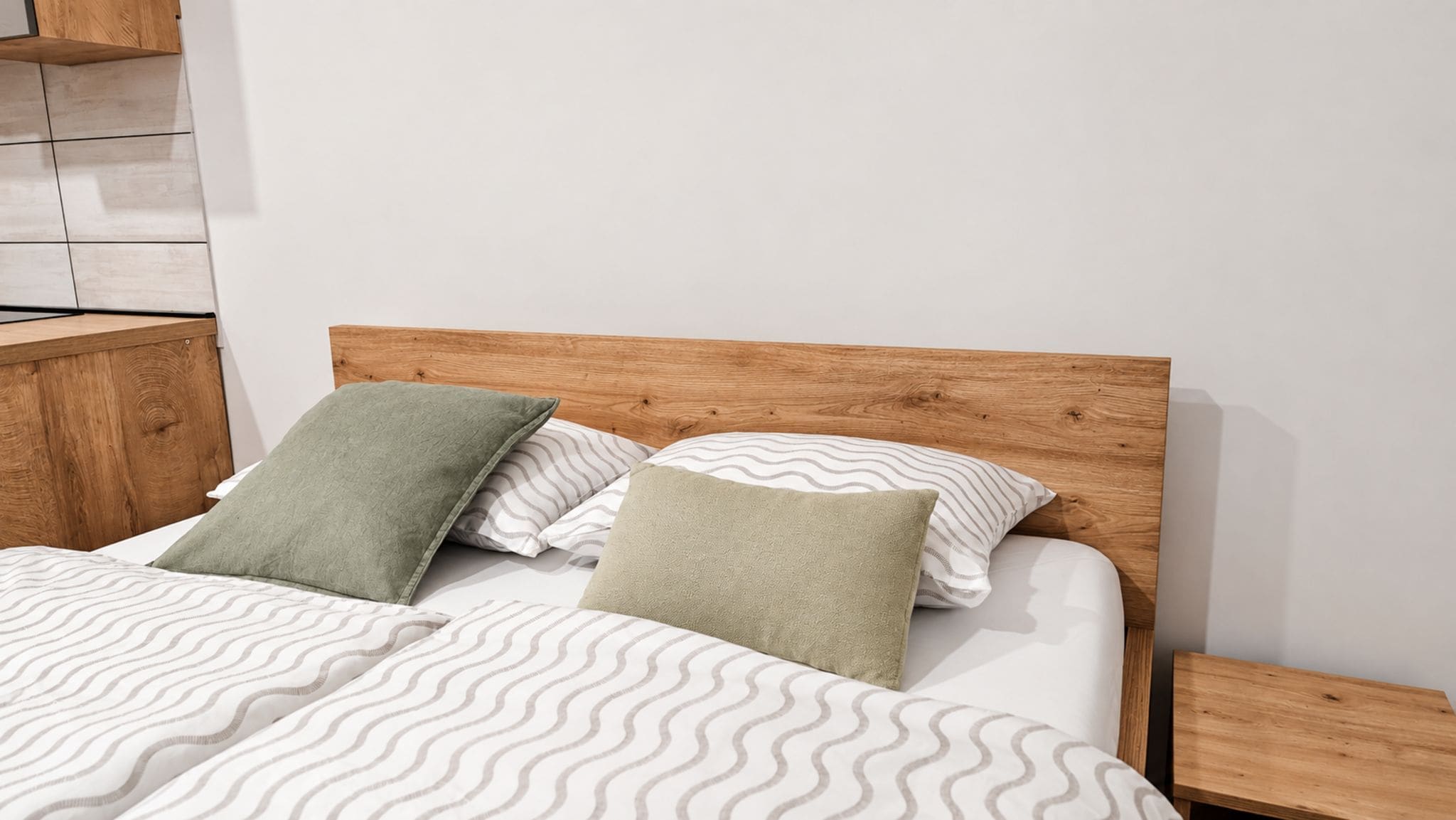Un lit avec une tête de lit en bois, deux oreillers et une couvre-lit à motifs.