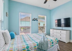 Een slaapkamer met een bed, een dressoir, een televisie en een balkon met uitzicht.